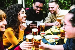 Happy diverse friends drinking beer at brewery pub - Group of young people having fun together at backyard home party - Friendship concept